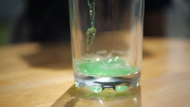 Splashing juice falling in an empty glass standing on a table in slow motion — Stock Video