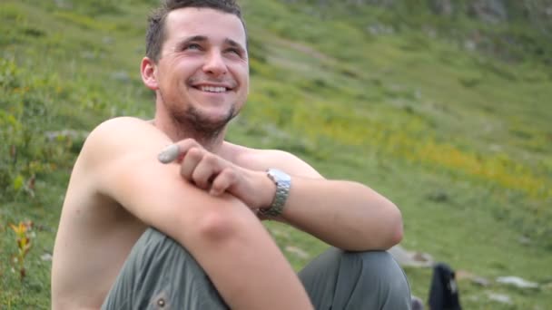 Alegre escalador sentado y sonriendo en las montañas de Georgia en verano en slo-mo — Vídeo de stock
