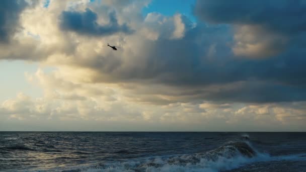 A viharos Fekete-tenger egy repülő helikopter a naplementében nyáron slo-Mo
