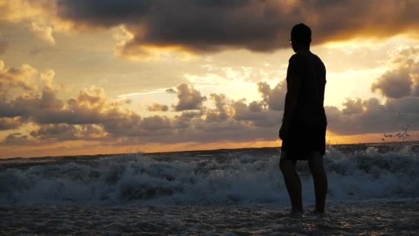 Молодой человек смотрит на бурное морское побережье с гигантскими волнами в Грузии в сло-мо — стоковое видео