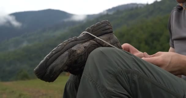 Un homme joyeux assis et réparant une semelle de bottes avec une corde dans les montagnes à Pékin — Video