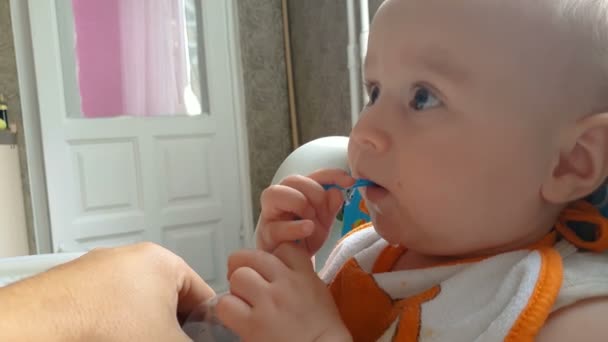 Adorável bebê bebe água através de uma palha de plástico em um apartamento no verão em slo-mo — Vídeo de Stock