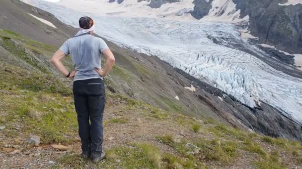 Hombre impresionado de pie y mirando una pendiente empinada nevada en Georgia en verano en slo-mo — Vídeos de Stock