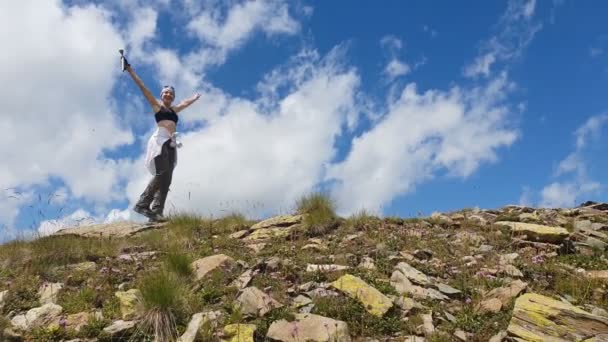 Mujer montañista va, sonriendo y levantando las manos sobre una montaña en slo-mo — Vídeos de Stock