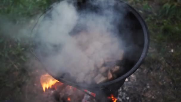 Small steaks in a round metallic tray are baking outdoors in summer in slo-mo — Stock Video