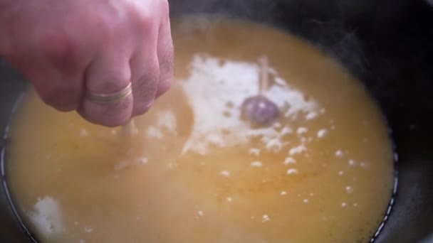 Pequenos pedaços de carne fervendo em uma panela grande com sopa azul ao ar livre em câmera lenta — Vídeo de Stock