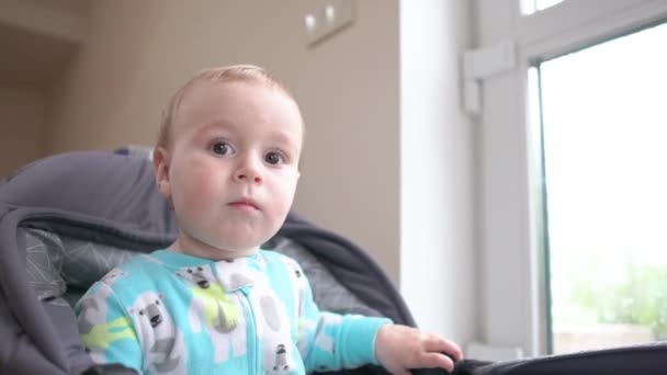 Sarı takım elbiseli neşeli bebek bebek arabasında oturur ve bir odada sallar. — Stok video