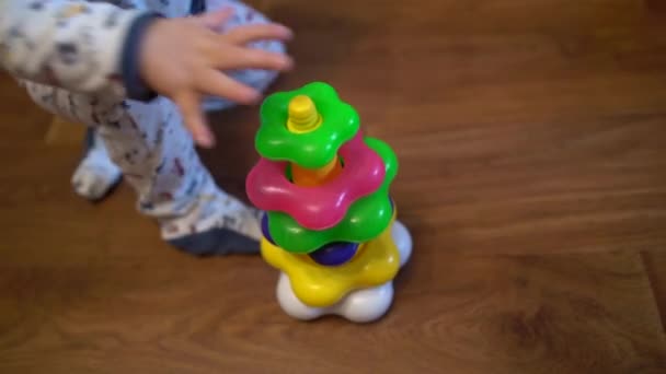 Uma criança pequena é jogada com um brinquedo - uma pirâmide com anéis, vista do topo . — Vídeo de Stock