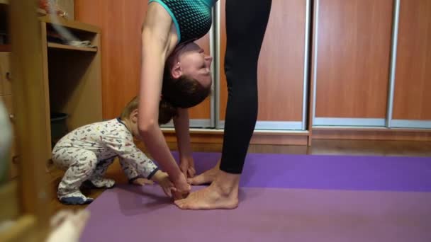 Mamma gör yoga hemma och liten unge spela arround. — Stockvideo