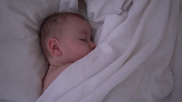 Un bambino addormentato carino sdraiato sotto una coperta bianca al rallentatore — Video Stock