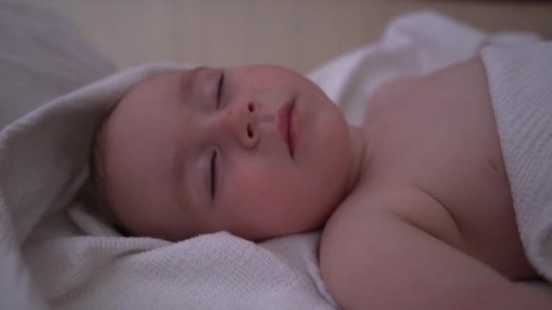 Un niño pequeño duerme dulcemente boca arriba en la cama grande, en cámara lenta — Vídeos de Stock