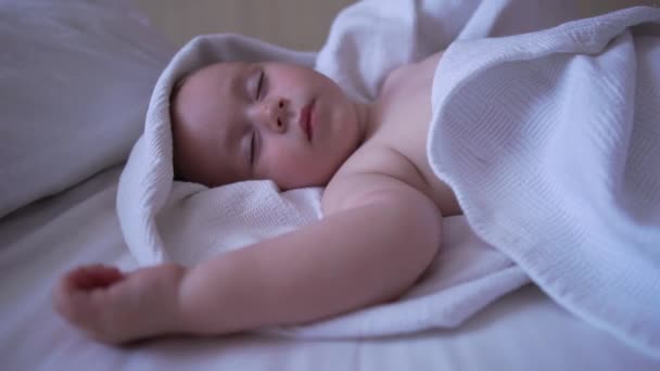 Un lindo niño desnudo duerme con las manos en alto en una cama grande en cámara lenta — Vídeos de Stock