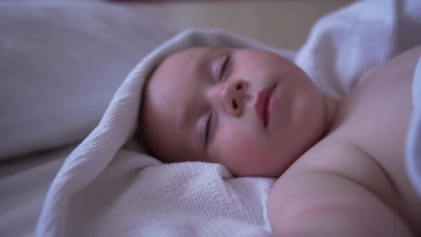 Pěkné nahé dítě spí s rukama nahoře na velké posteli v pomalém pohybu — Stock video