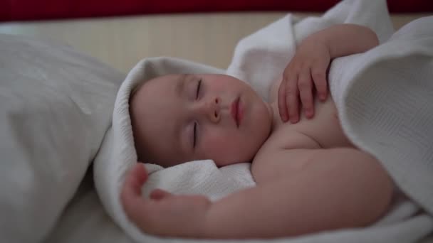 예쁜 아기는 슬로우 모션으로 큰 침대에 손을 들고 자고 있습니다. — 비디오