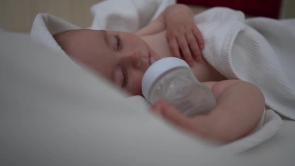一个熟睡的小男孩拿着一个瓶子在慢动作 — 图库视频影像