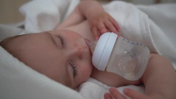 The baby sweetly sleeps with a bottle near his mouth, slow motion — Stock Video