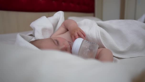 Маленька дитина солодко спить з пляшкою біля рота, повільний рух — стокове відео