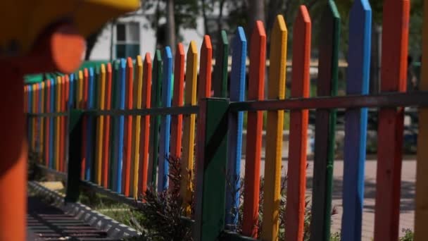 Valla colorida del arco iris del patio de recreo en día soleado, cámara lenta — Vídeo de stock