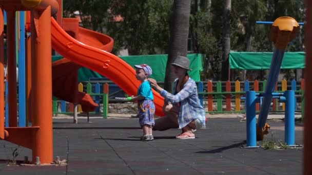 Anne oyun oynarken güneş kremi ile oğlunu lekeler, yavaş hareket — Stok video