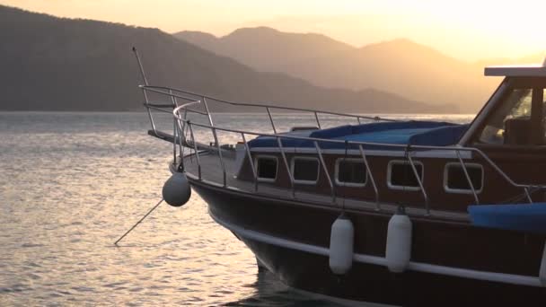 Barco amarrado en el mar entre las montañas al atardecer en cámara lenta — Vídeo de stock