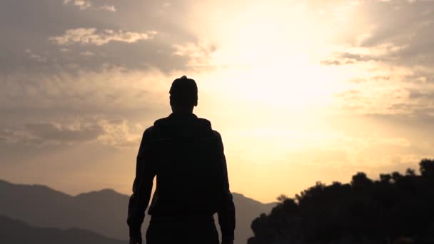 Хлопець кидає руки в сторони в захваті від природи на заході сонця, повільний рух — стокове відео