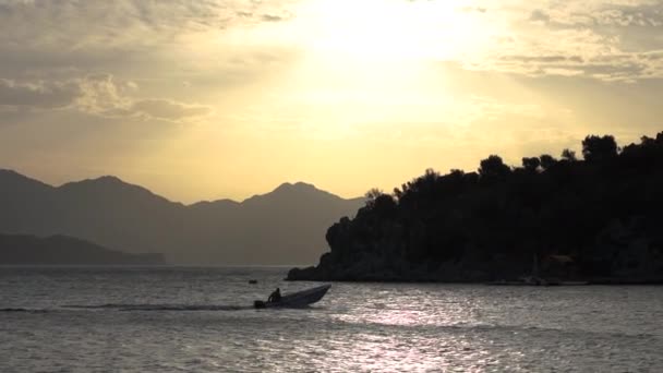 Een kleine boot vaart in een prachtige baai tijdens zonsondergang in slow motion — Stockvideo