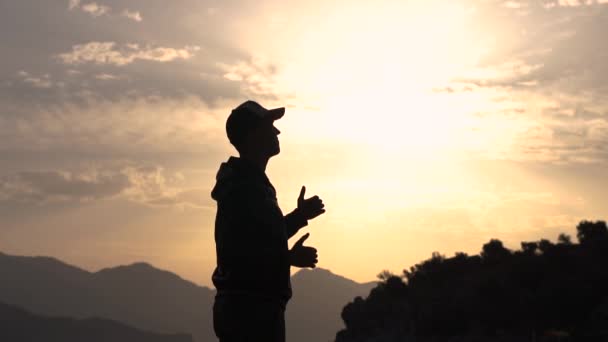 Bir adam gülümsüyor ve yavaş çekimde gün batımında yan duran jest ok gösterir — Stok video