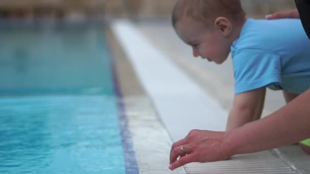 De moeder en kleine baby aanraken het zwembad water met interesse in slow motion — Stockvideo