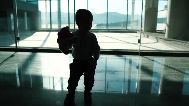 Um menino com um brinquedo está andando ao redor do aeroporto em câmera lenta — Vídeo de Stock