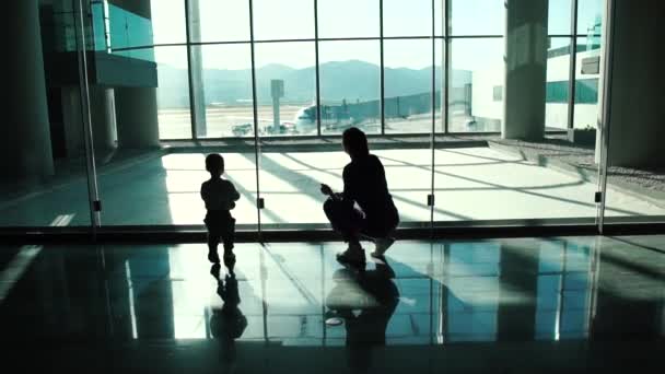 Mały chłopiec z matką patrzeć na samoloty na lotnisku w zwolnionym tempie — Wideo stockowe