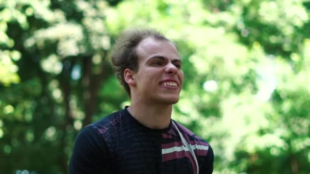 Angry Young Man met een verwarmde grimas het verhogen van de handen in een groene steeg in slo-mo — Stockvideo