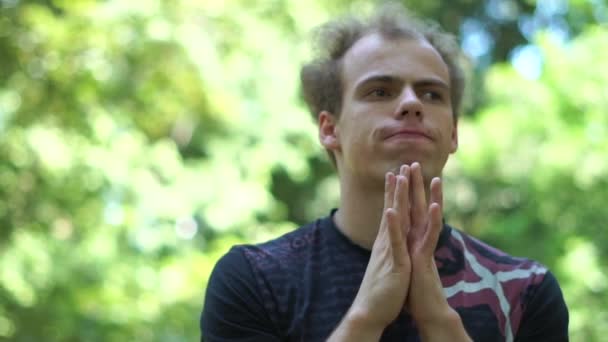 Álmodozás fiatalember dobolás ujjai az állán egy zöld parkban slo-Mo — Stock videók