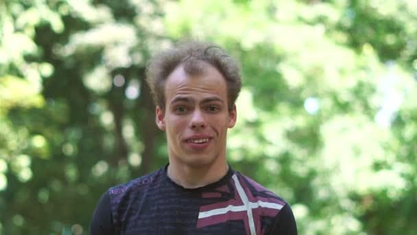 Sorpreso giovane uomo sorridente e ottenere una rivelazione in un parco verde a Slo-mo — Video Stock