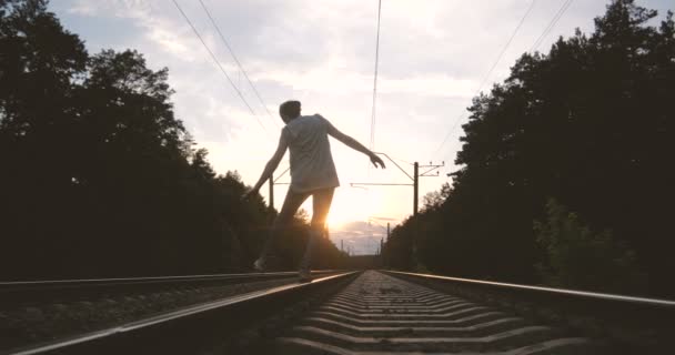 4k - Un tipo tratando de mantener su equilibrio en una vía férrea, cámara lenta — Vídeos de Stock