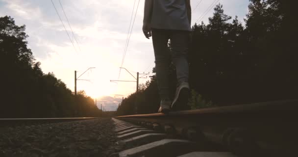 4k - Um jovem caminha ao longo de uma trilha ferroviária durante o pôr do sol, câmera lenta — Vídeo de Stock