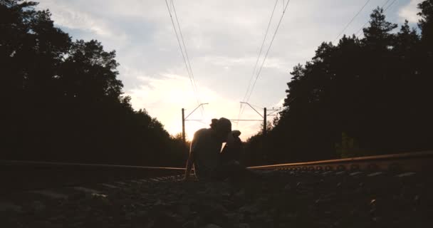 4K-έφηβος ανεβαίνει από το έδαφος μεταξύ των σιδηροτροχιών, αργή κίνηση — Αρχείο Βίντεο