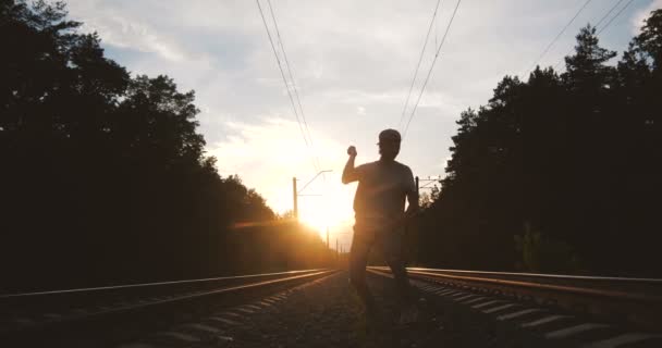 4k - The boy dancing krump near the railway track against the sun, slow motion — Stock Video