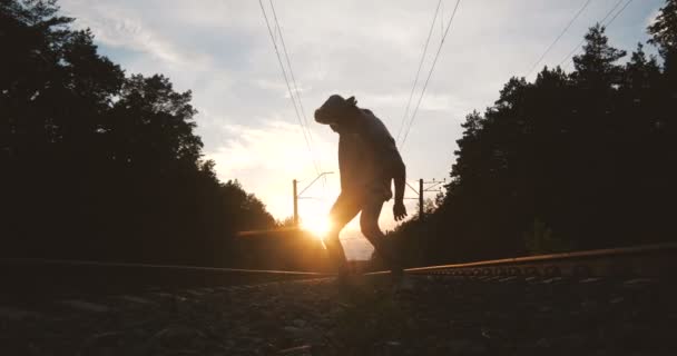 4k - A silhueta de um jovem dançando krump perto da linha férrea contra o sol, câmera lenta — Vídeo de Stock