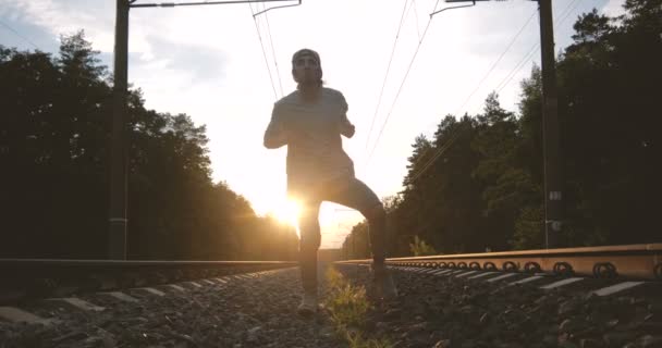 4k-a srác a kupakot táncolnak a krump a természet közelében a vasúti naplemente alatt, lassított — Stock videók
