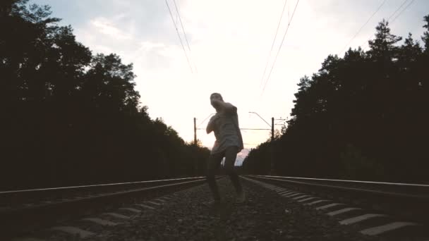 Um jovem dança um krump perto do trilho durante o pôr do sol, câmera lenta — Vídeo de Stock