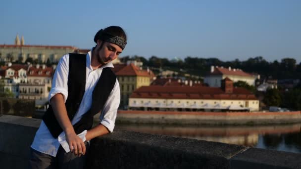 4k - панк-хлопець палить на мосту на тлі старого міста, повільний рух — стокове відео