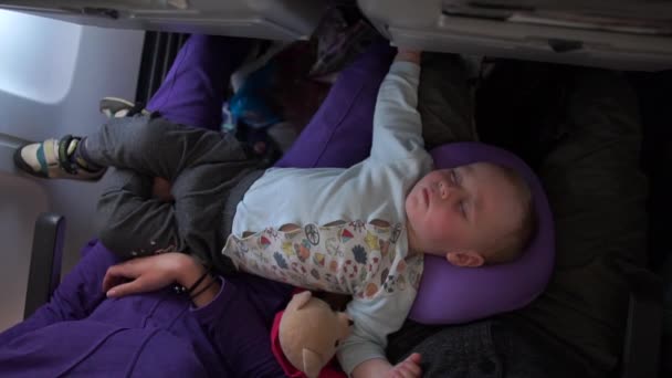 Pequeno bebê dormindo em um avião deitado em mãe e pai em câmera lenta — Vídeo de Stock