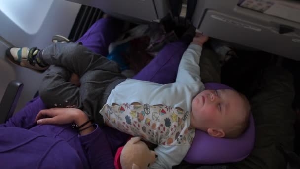 Pequeño bebé lindo durmiendo en un avión acostado en mamá y papá en cámara lenta — Vídeos de Stock