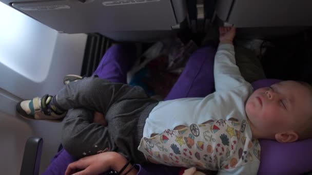 Niño pequeño durmiendo en un avión acostado en las piernas de mamá y papá en cámara lenta — Vídeos de Stock