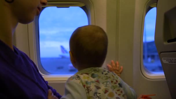 La mamma e il bambino guardano fuori dalla finestra dell'aereo al rallentatore — Video Stock