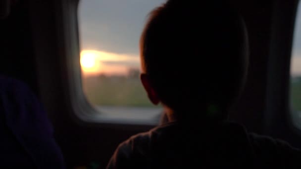 The small boy looks at the rising sun through the plane window in slow motion — Stock Video