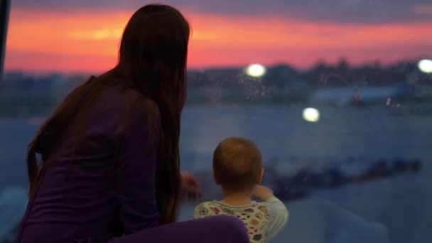 Una morena y su hijo están en la ventana del aeropuerto en cámara lenta — Vídeos de Stock