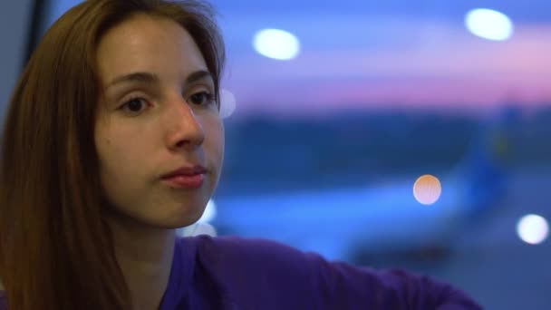 Chica seria de pie en la ventana del aeropuerto esperando un vuelo en cámara lenta — Vídeos de Stock