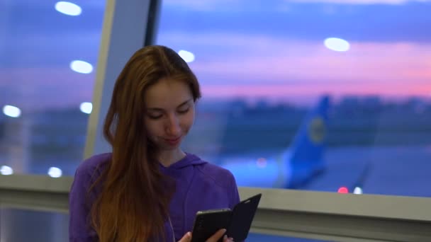 Menina digita uma mensagem no telefone no aeroporto ao pôr do sol em câmera lenta — Vídeo de Stock