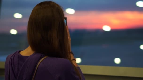 Mutlu kadın yavaş çekimde havaalanı penceresinden telefonda bir fotoğraf yapar — Stok video